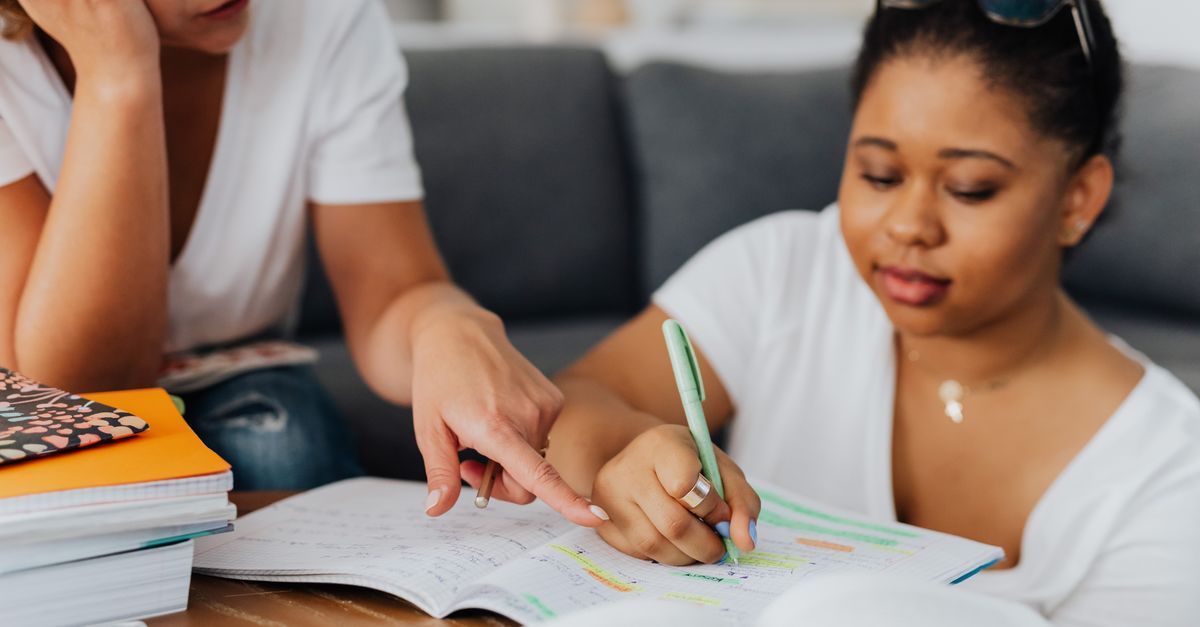 Two women studying with notebooks and pens in a tutoring session.